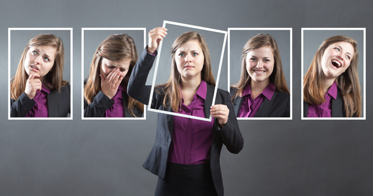 Concept photo for personality, character and emotional expression. A woman in business suit holding up a photo of herself in front of her with various range of emotional expressions exhibited in the background wall behind her. From happiness to sadness, anger to joy, apprehension to confidence. Photographed in panoramic horizontal format in studio.